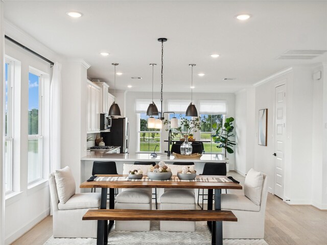 dining space featuring light hardwood / wood-style floors and crown molding