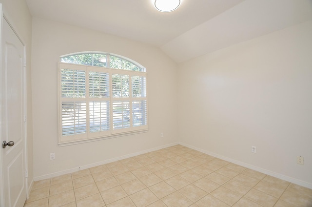 tiled spare room featuring lofted ceiling