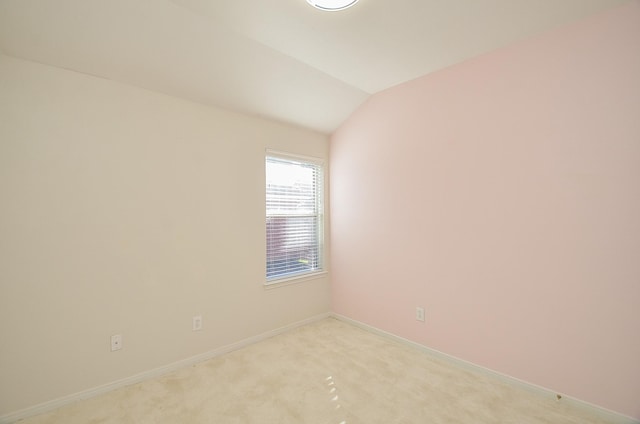 spare room with light colored carpet and vaulted ceiling