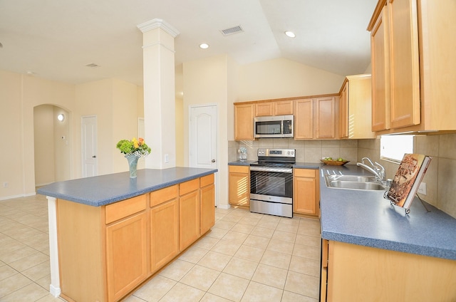 kitchen with light brown cabinets, stainless steel appliances, vaulted ceiling, and sink