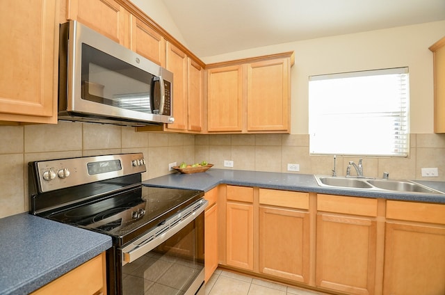 kitchen featuring decorative backsplash, sink, light tile patterned flooring, and appliances with stainless steel finishes