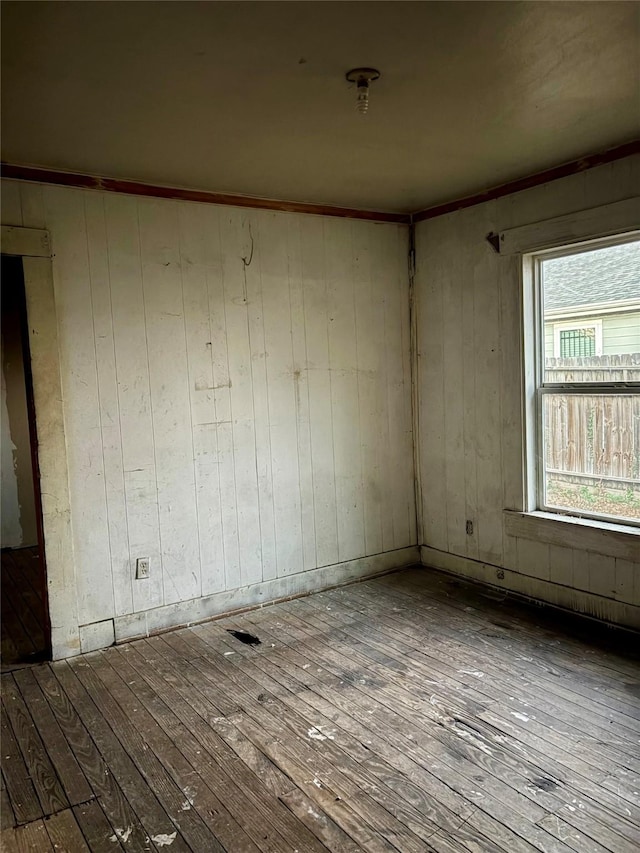 spare room featuring wood-type flooring and wooden walls