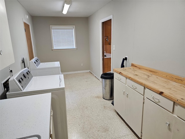 laundry room with washing machine and dryer, cabinet space, and baseboards