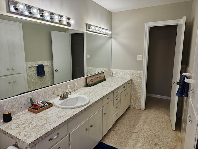 bathroom featuring a wainscoted wall, baseboards, vanity, and tile walls