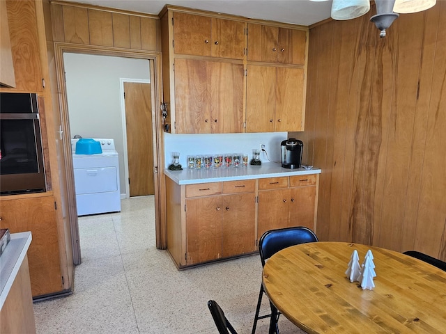 kitchen with wooden walls, stainless steel oven, and washer / clothes dryer