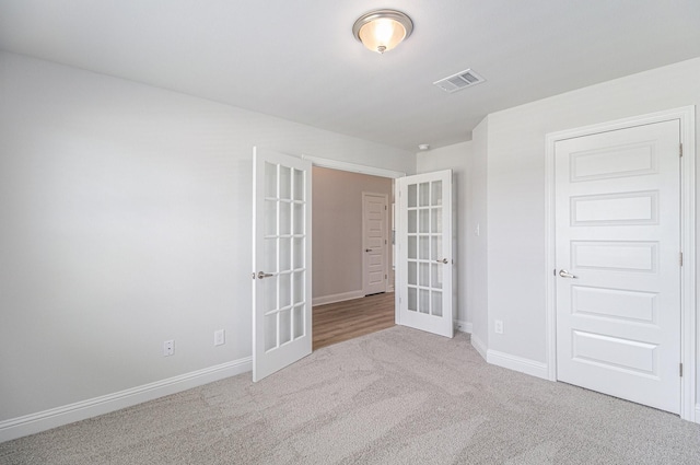 unfurnished room with light carpet and french doors