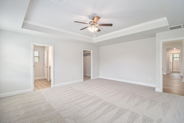 unfurnished bedroom featuring ceiling fan, a raised ceiling, and ornamental molding