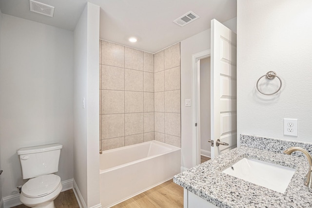 full bathroom with vanity, hardwood / wood-style flooring, toilet, and tiled shower / bath