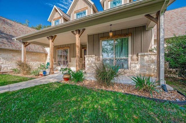 view of exterior entry with covered porch and a yard