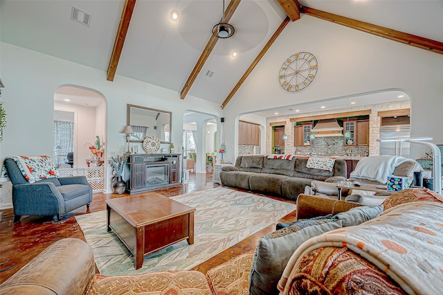 living room with beamed ceiling, light hardwood / wood-style floors, and high vaulted ceiling