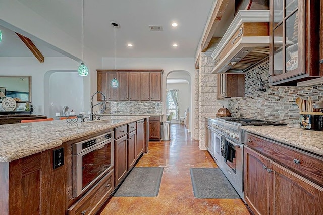 kitchen with decorative backsplash, custom exhaust hood, stainless steel appliances, sink, and decorative light fixtures