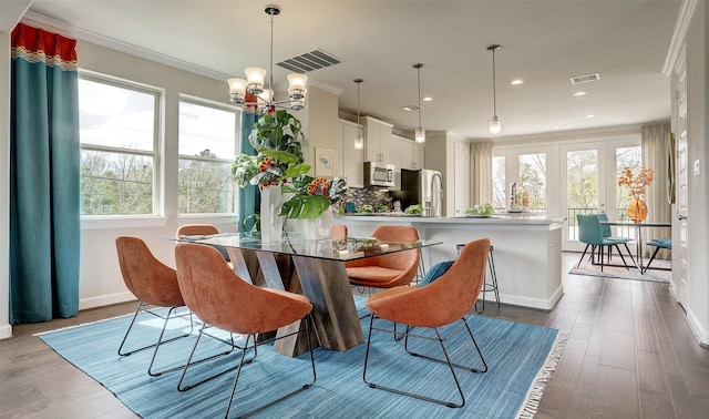 dining space featuring hardwood / wood-style flooring, ornamental molding, and a chandelier