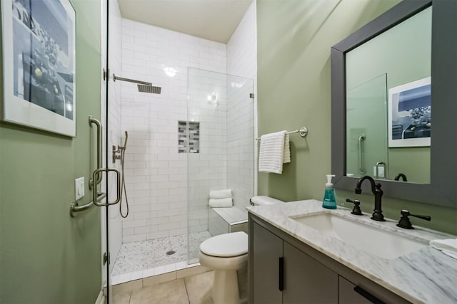 bathroom featuring tile patterned flooring, vanity, toilet, and walk in shower