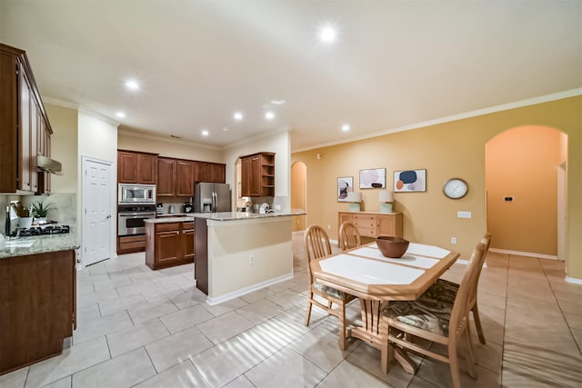 kitchen featuring decorative backsplash, ornamental molding, stainless steel appliances, light tile patterned floors, and a center island