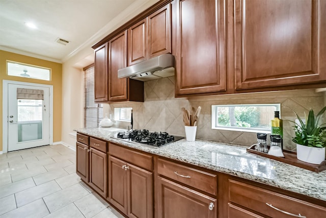 kitchen featuring backsplash, light stone counters, stainless steel gas cooktop, and ornamental molding