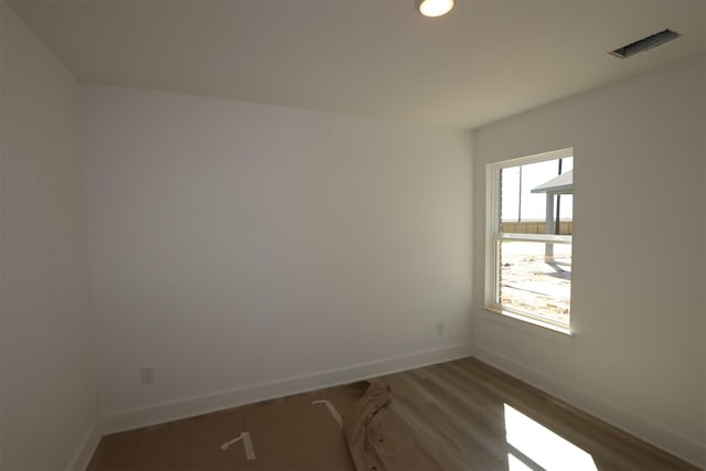 spare room featuring visible vents, baseboards, and wood finished floors