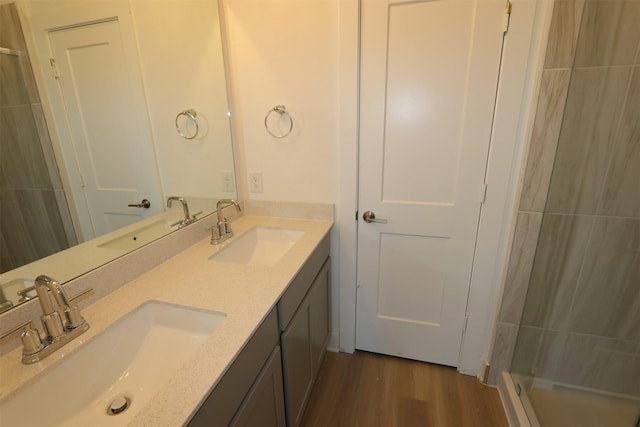 full bath with double vanity, wood finished floors, and a sink