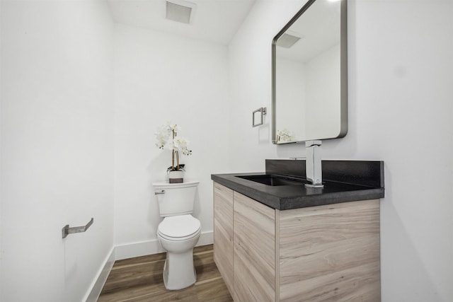 bathroom with hardwood / wood-style floors, vanity, and toilet