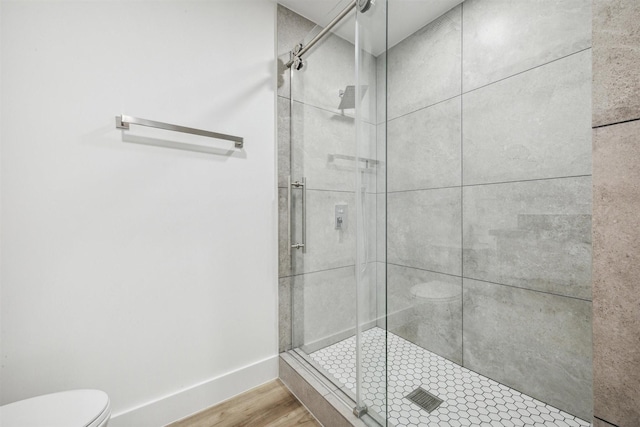 bathroom featuring hardwood / wood-style flooring, toilet, and a shower with shower door