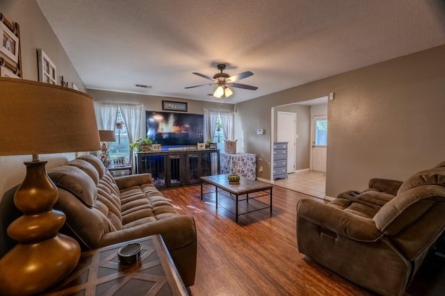 living room with hardwood / wood-style floors, plenty of natural light, ceiling fan, and a textured ceiling