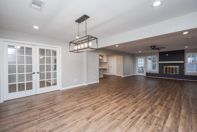 unfurnished living room with a fireplace, ceiling fan, hardwood / wood-style floors, and french doors