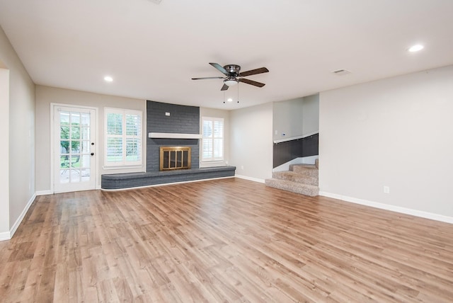 unfurnished living room featuring ceiling fan, a fireplace, and light wood-type flooring