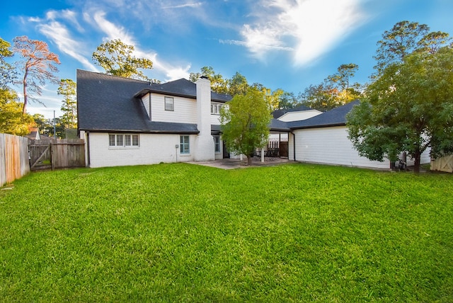 rear view of house with a lawn and a patio