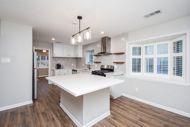 kitchen with white cabinetry, a healthy amount of sunlight, wall chimney range hood, and appliances with stainless steel finishes