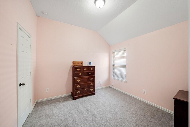 bedroom with light colored carpet and lofted ceiling