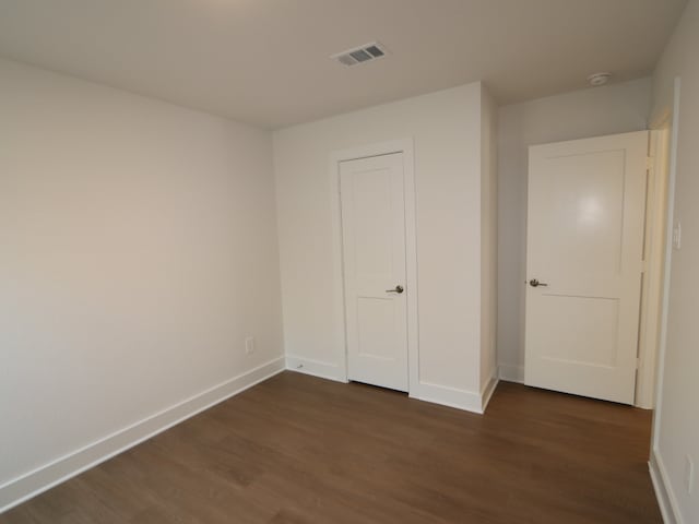 unfurnished bedroom with visible vents, baseboards, and dark wood-style floors