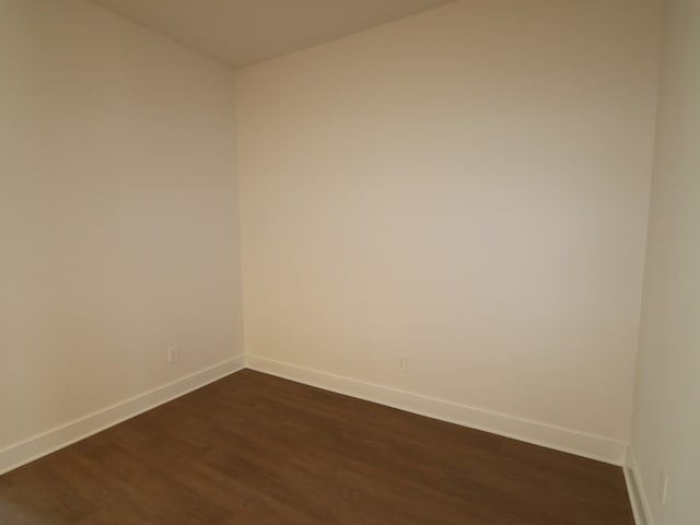 unfurnished room with baseboards and dark wood-style flooring