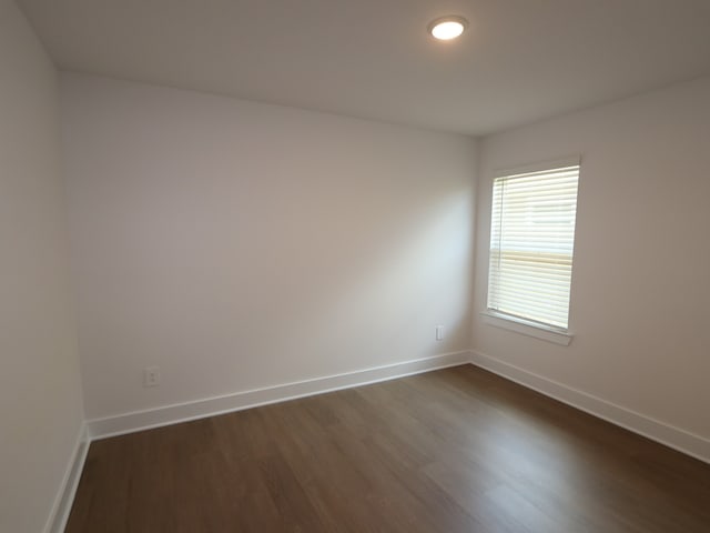 empty room featuring baseboards and dark wood-type flooring