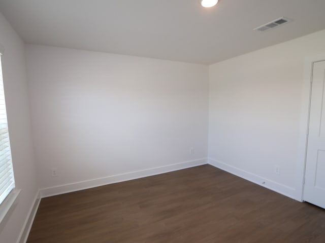 spare room with dark wood-type flooring, baseboards, and visible vents