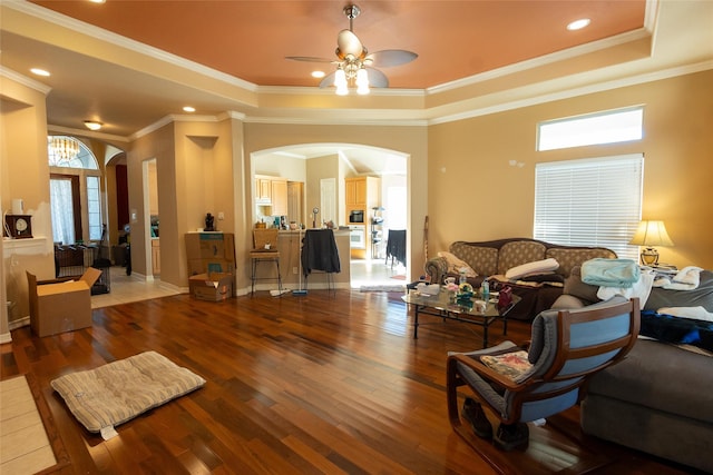 living room with hardwood / wood-style floors, a raised ceiling, ceiling fan, and crown molding