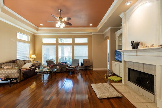 living room with a tiled fireplace, ceiling fan, plenty of natural light, and wood-type flooring