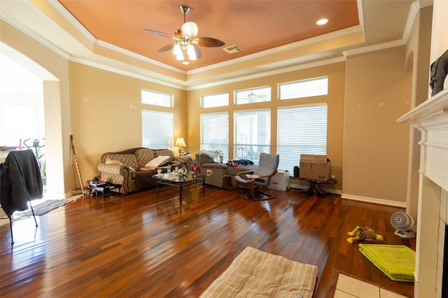 living room featuring hardwood / wood-style flooring, a raised ceiling, ceiling fan, and ornamental molding