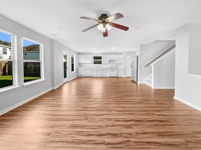 unfurnished living room featuring ceiling fan and light wood-type flooring