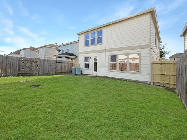 rear view of property featuring a yard and central air condition unit