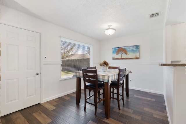 dining space featuring a textured ceiling and dark hardwood / wood-style floors