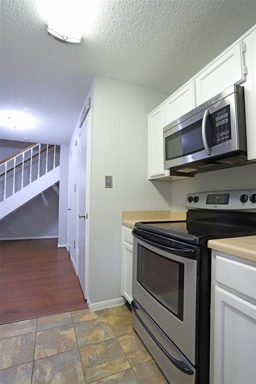 kitchen featuring a textured ceiling, stainless steel appliances, and white cabinetry