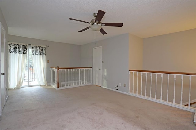 empty room with ceiling fan, light colored carpet, and a textured ceiling