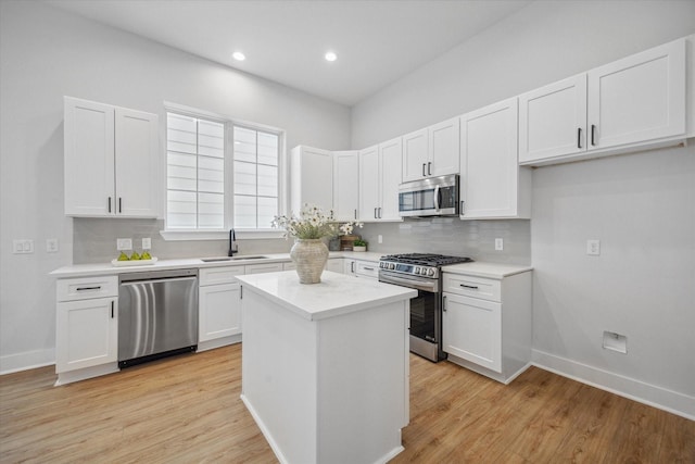 kitchen featuring stainless steel appliances, sink, light hardwood / wood-style flooring, a center island, and white cabinetry