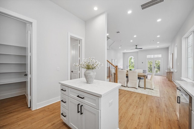 kitchen with french doors, white cabinets, ceiling fan, a kitchen island, and light hardwood / wood-style floors