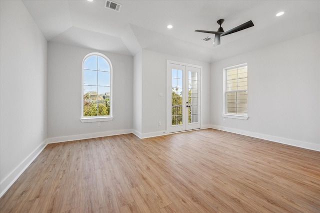 empty room featuring french doors, light wood-type flooring, ceiling fan, and a healthy amount of sunlight