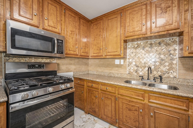 kitchen featuring backsplash, light stone counters, sink, and appliances with stainless steel finishes