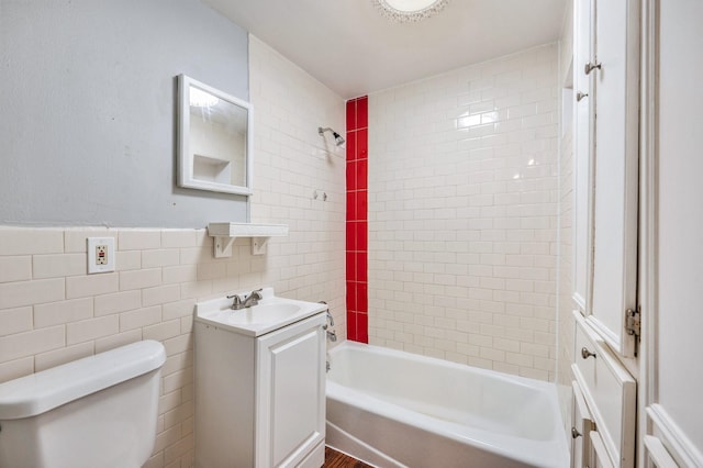 full bathroom featuring vanity, tiled shower / bath combo, tile walls, and toilet