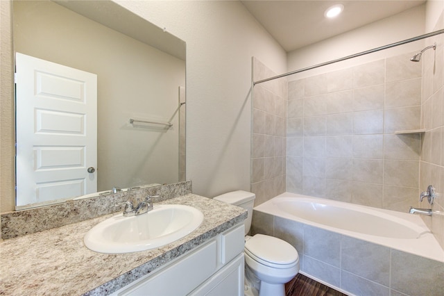 full bathroom featuring vanity, tiled shower / bath combo, and toilet