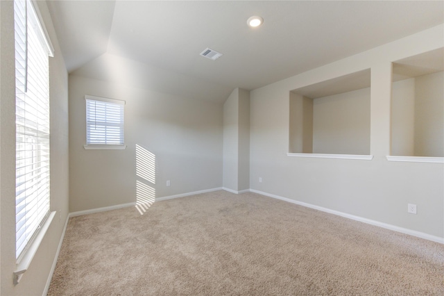 carpeted empty room featuring vaulted ceiling