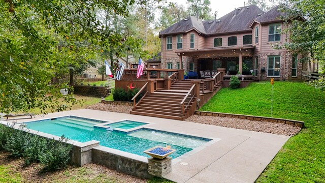 rear view of property featuring a yard and a pool with hot tub