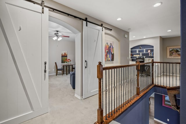 corridor featuring a barn door, built in shelves, and carpet